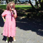 Tessa, mic in hand, stands in front of the glade where we like to perform in Coyle Park, Point Chevalier